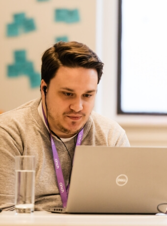 A man wearing a cinch lanyard and working at a laptop