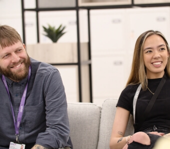 Two people sat on a sofa in the cinch office listening to someone speak